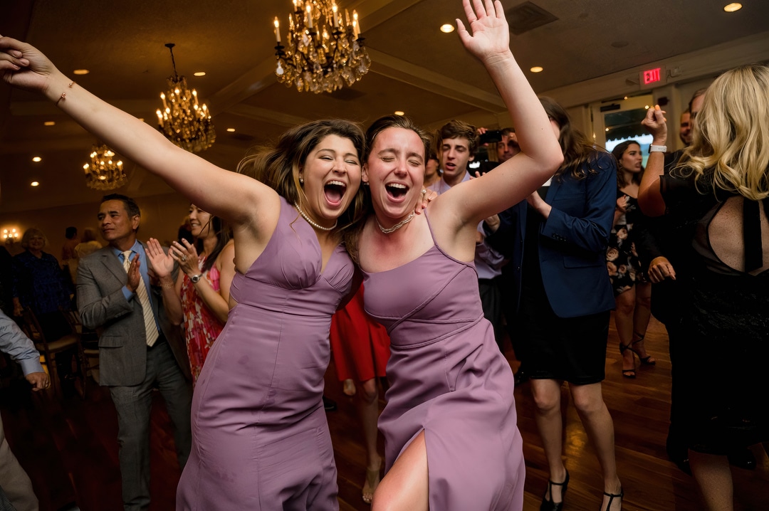 Bridesmaids smile and dance during a wedding reception.