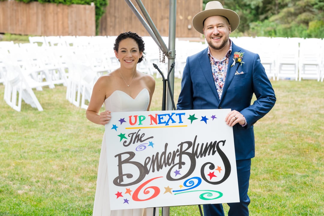 A couple holds a sign that welcomes guests to their wedding at the Gardens of Stonebridge