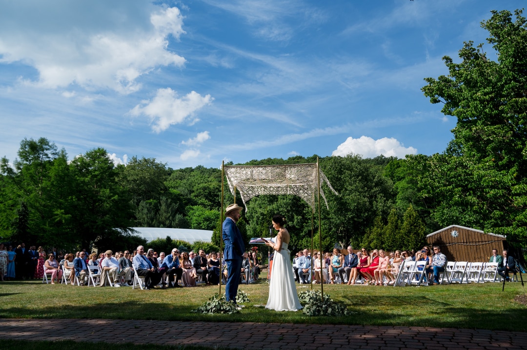 Overall view of an outdoor Gardens of Stonebridge wedding beneath blue skies with wispy clouds.
