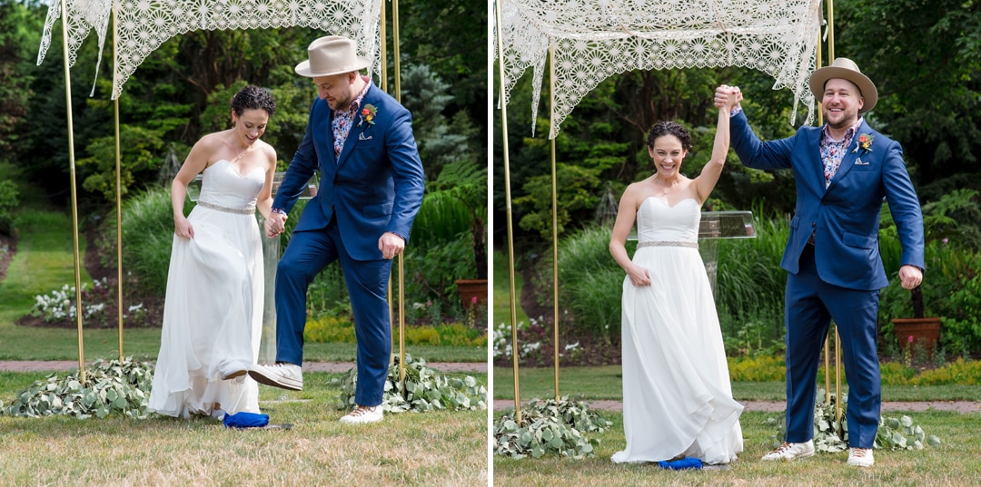 A couple stomp on a glass then raise their hands during their Gardens of Stonebridge Wedding.