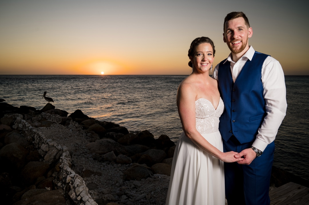 A married couple stands on the beach in Aruba at sunset after their destination wedding.