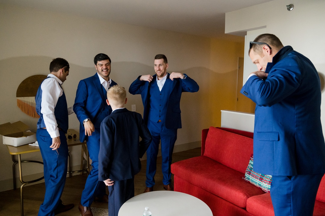 A groom and his groomsmen put on their blue suits as they prepare for a wedding.