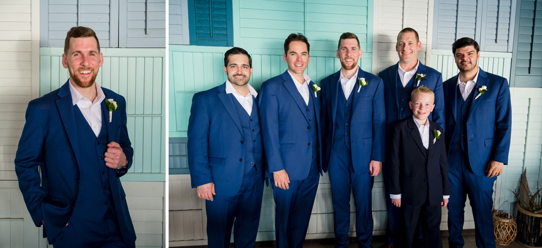 A groom and his groomsmen wear blue suits as they stand in front of a blue-colored wall in Aruba.