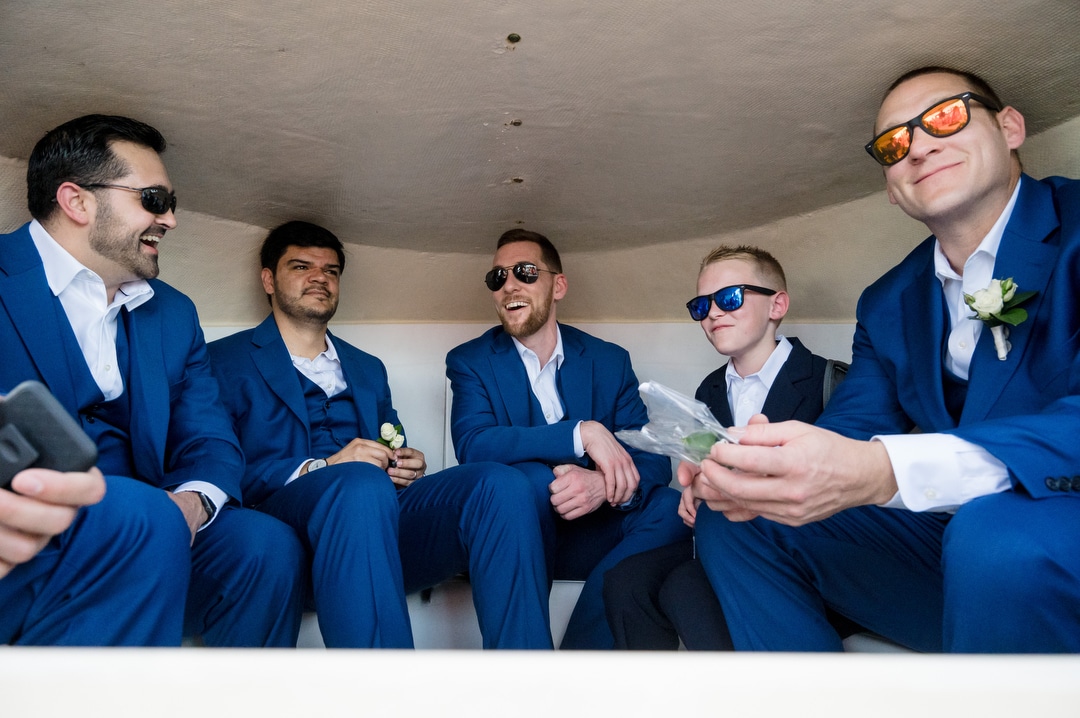 A groom and his groomsmen wear sunglasses as they ride in the cabin of a boat on the way to a wedding ceremony in Aruba.