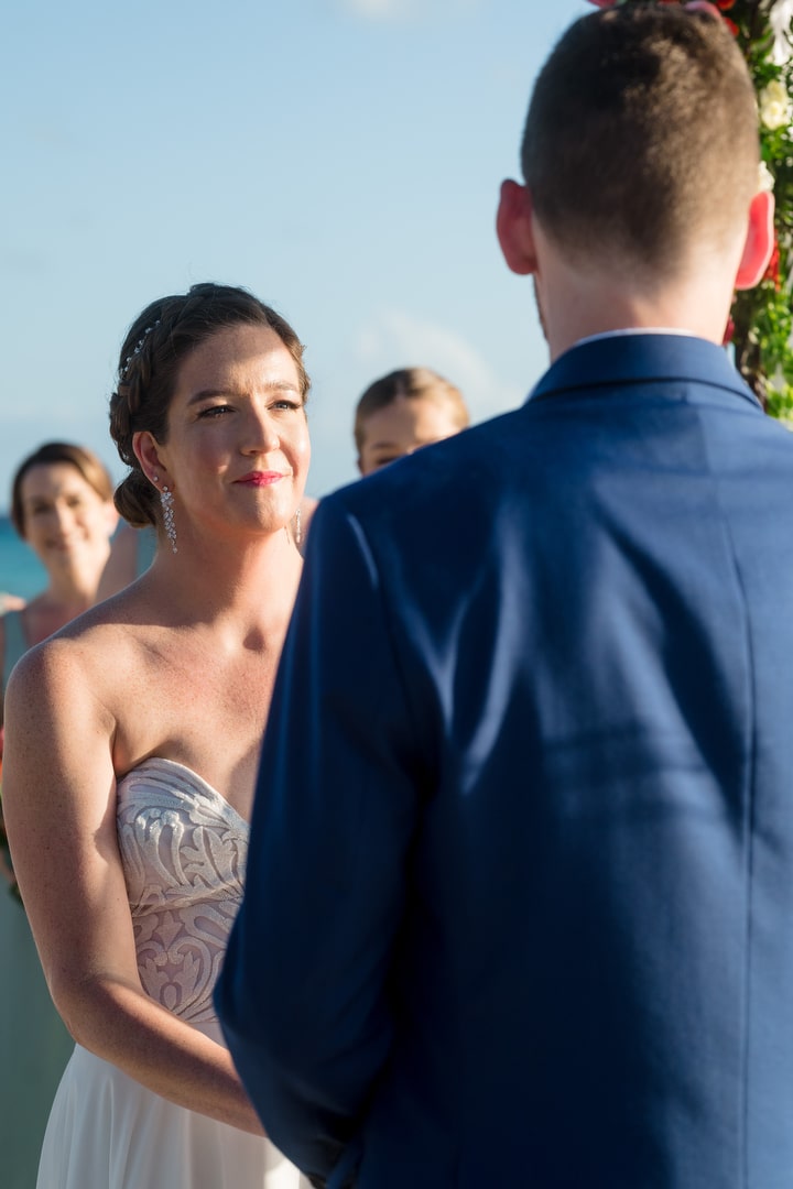 A bride looks at her groom as they exchange wedding vows on a beach in Aruba.