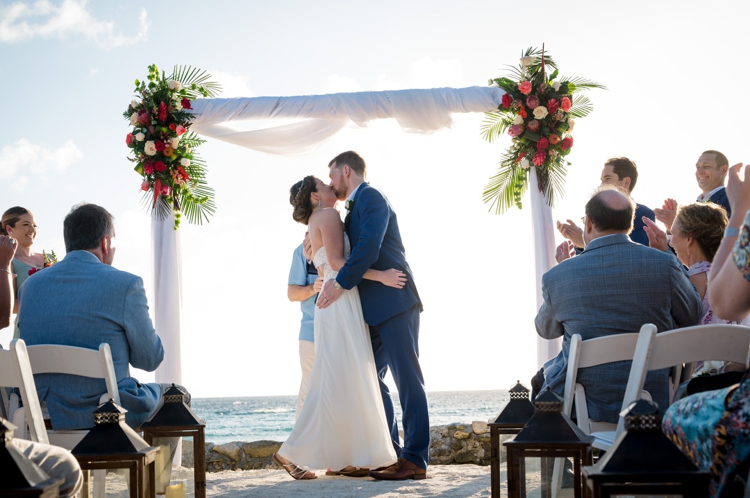 A couple kisses at end of their destination wedding on a beach in Aruba.