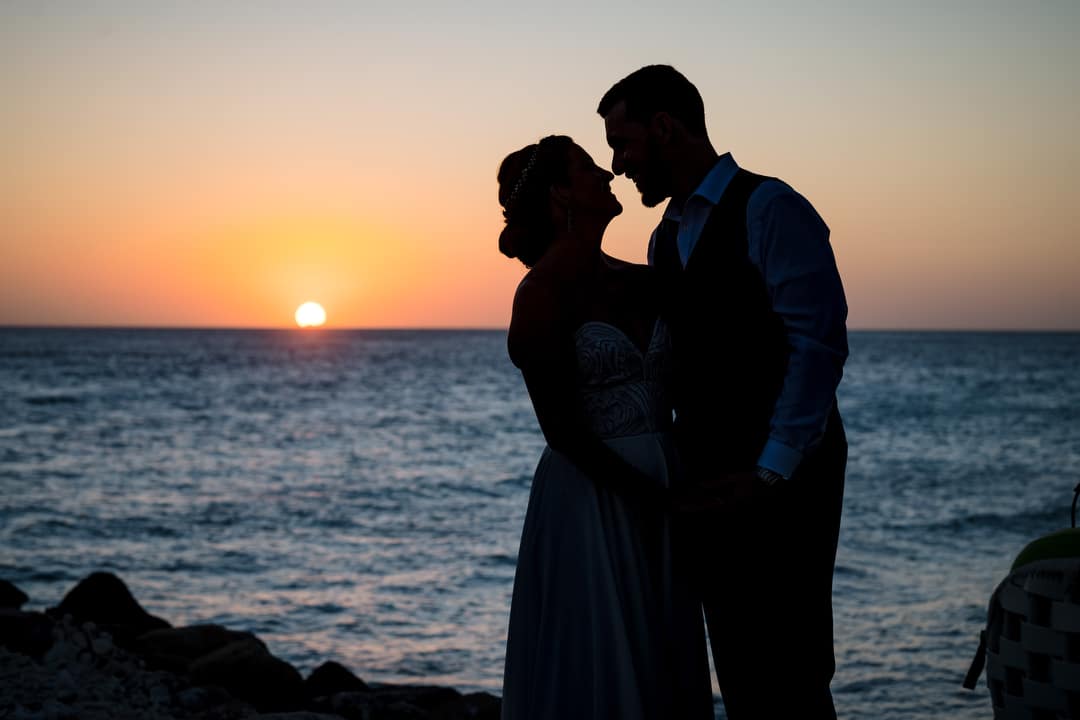 Silhouette photo of a bride and groom at sunset after their destination wedding in Aruba.