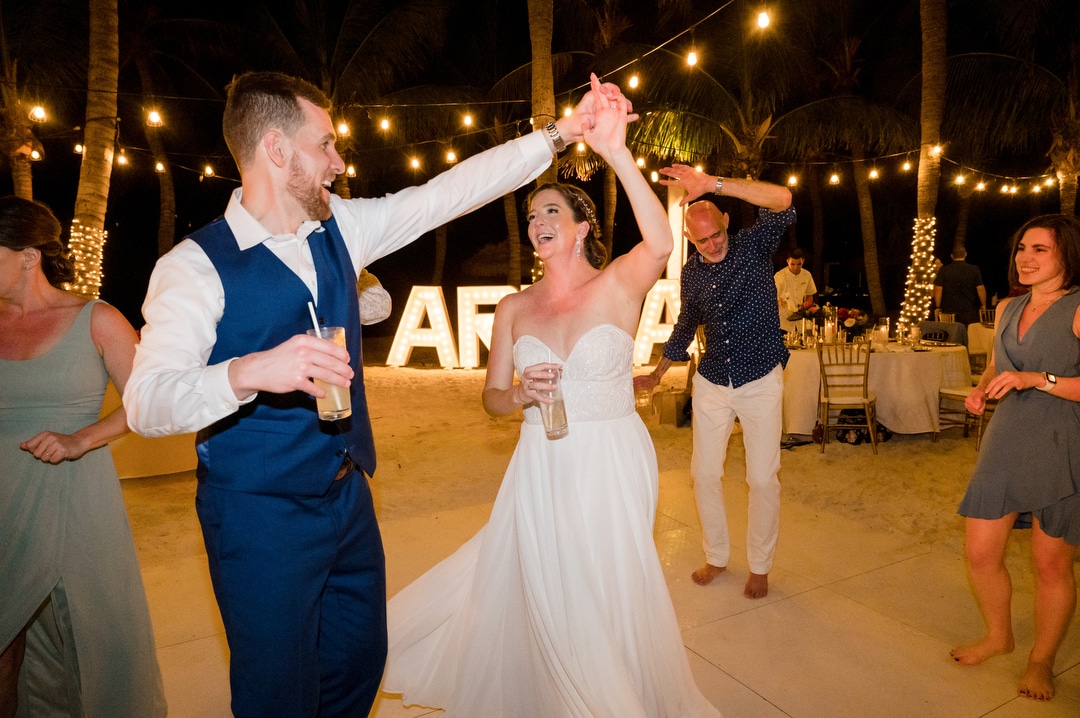 A newly married couple dances during their destination wedding on a beach in Aruba.