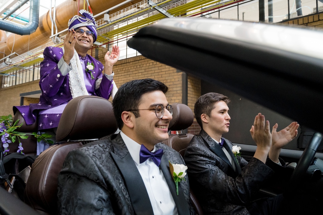 A groom dressed in South Asian garb for his wedding sits on the back of a convertible heading down the corridor at the Energy Innovation Center in Pittsburgh.