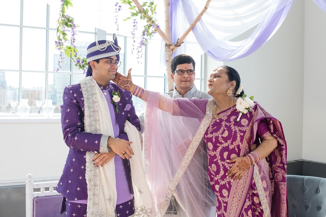 A mother wearing a sari reaches over to caress her son's face during a South Asian wedding at the Energy Innovation Center.