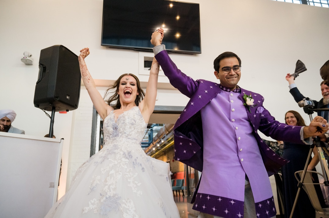 A couple celebrate as they enter their wedding reception at the Energy Innovation Center.