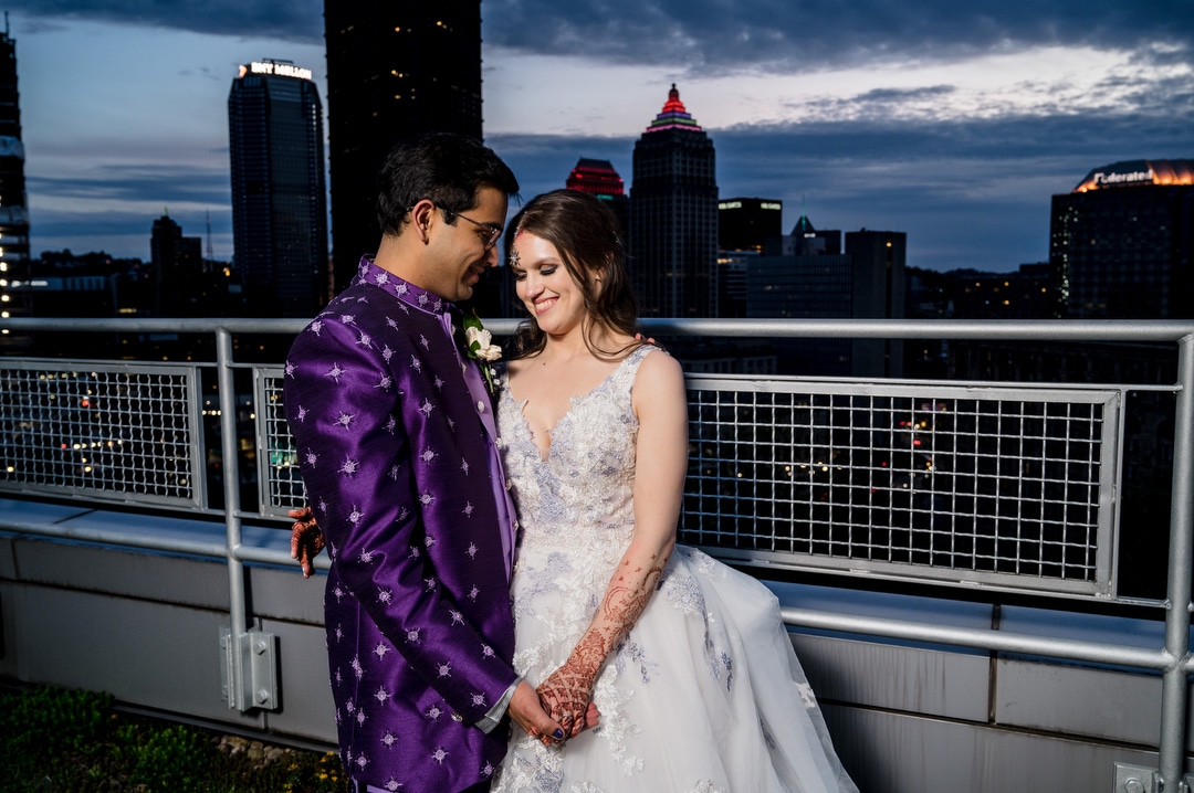A bride and groom pose for a portrait on the roof of the Energy Innovation Center during their wedding. The skyline of Pittsburgh is behind them.