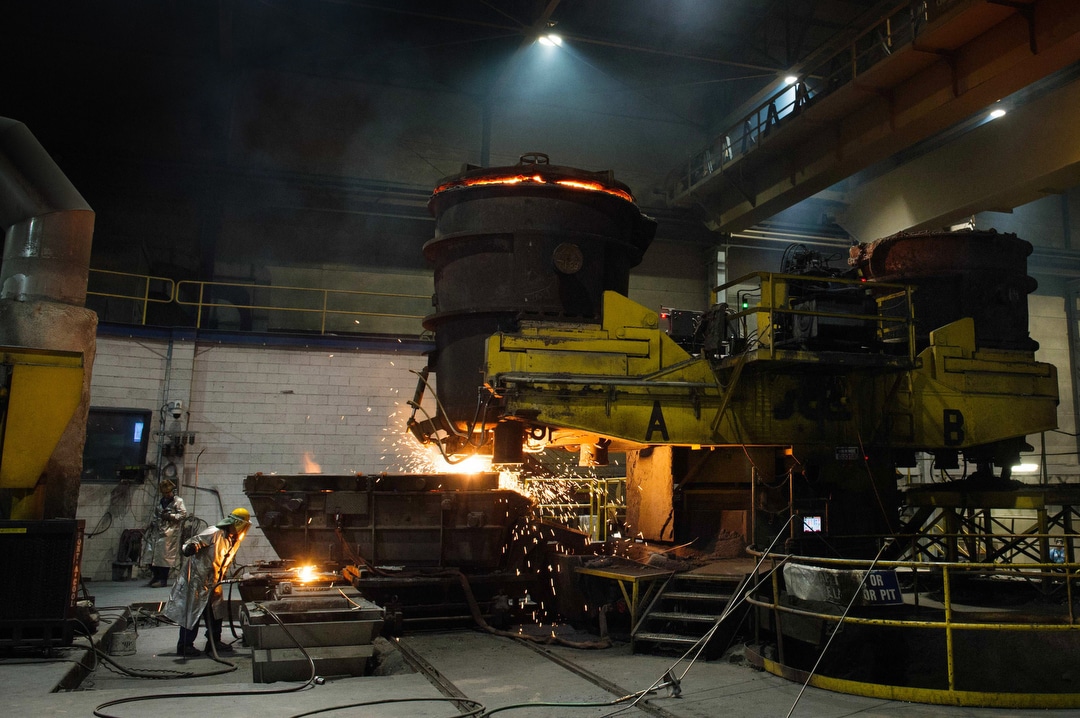 A steelworker wearing heat-resistant gear looks into a blast furnace at a steel mill near Pittsburgh.