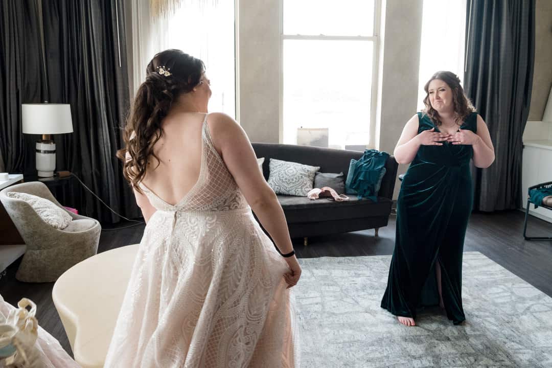 A bridesmaid reacts as she sees the bride in her dress in the brightly lit, light and airy suite at the Renaissance hotel in Pittsburgh.