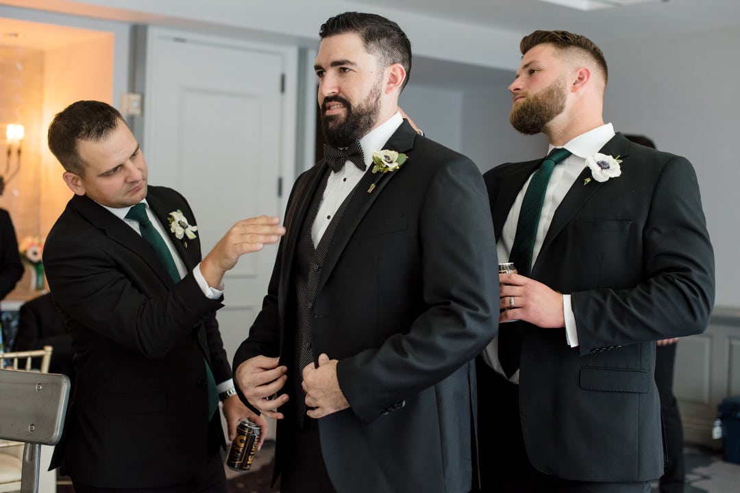 A groom is helped to get his tuxedo by his groomsmen.