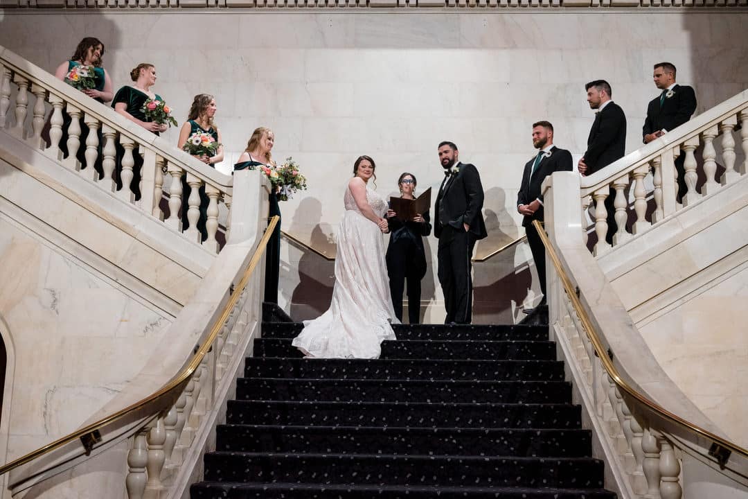 A bride and groom stand on the landing of the grand staircase during their wedding at the Renaissance in Pittsburgh.