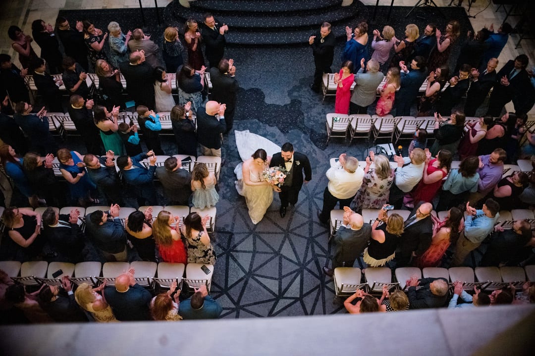 Seen from directly above, a bride and groom exit their wedding ceremony in the lobby of the Renaissance hotel in Pittsburgh.