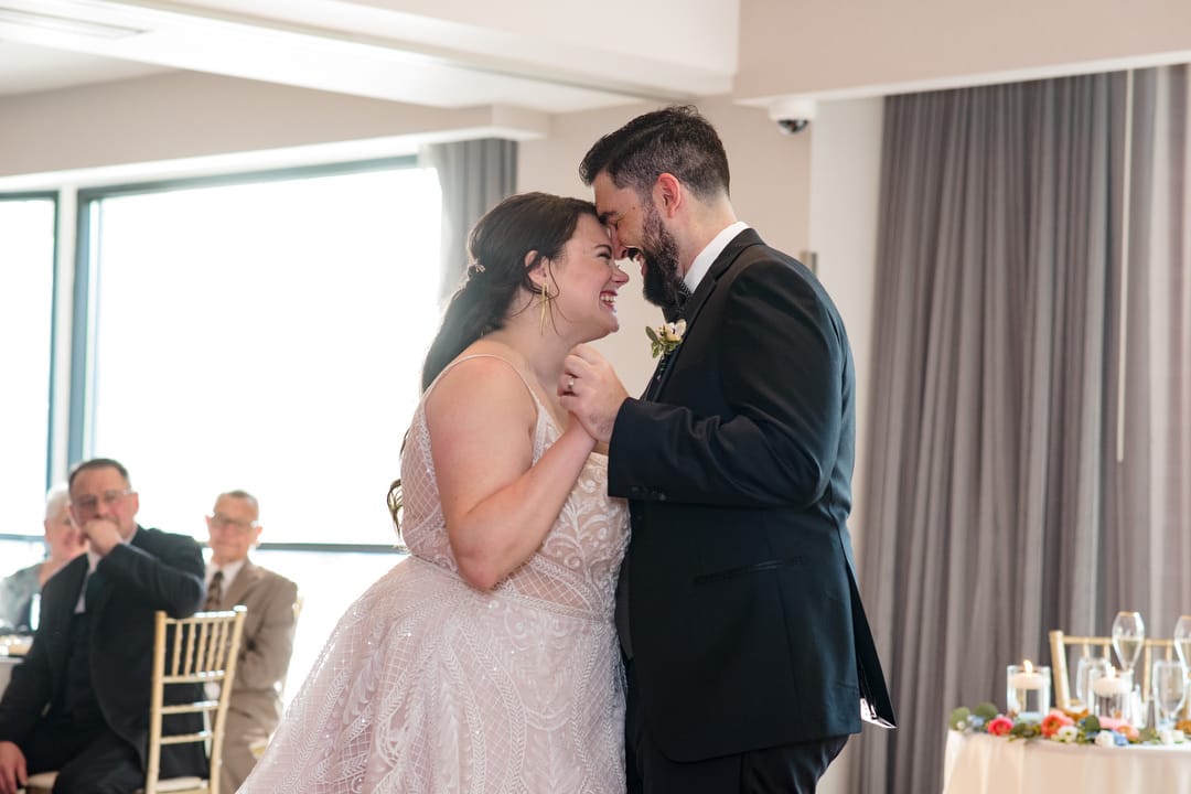 A bride and groom share a first dance as the sun shines through the windows of the Symphony Ballroom giving the wedding reception a light and airy feel.