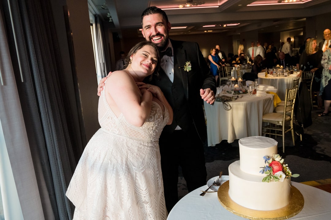 A bride and groom embrace after cutting their cake.