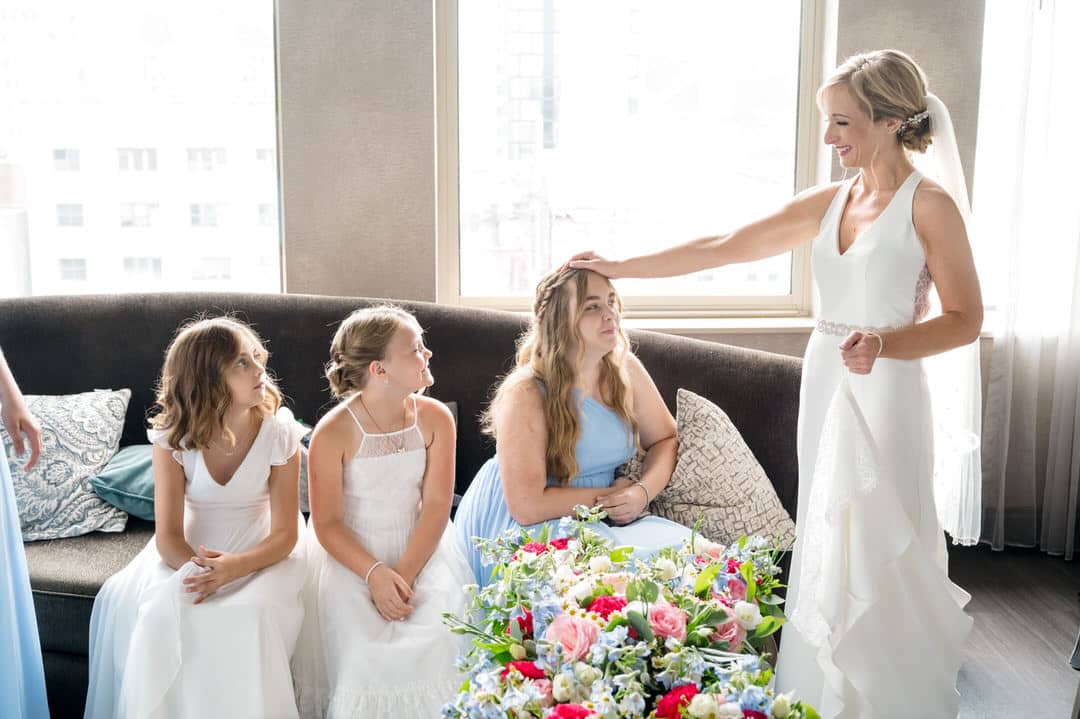A bride puts her hand on the head of a junior bridesmaid wearing a blue dress before a wedding at the Renaissance hotel in Pittsburgh.