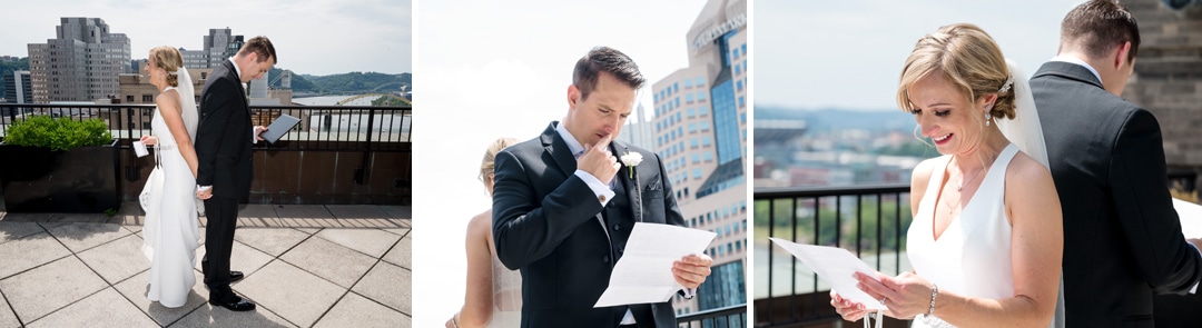 A bride and groom stand back-to-back as they read letters to each other on the balcony of the Renaissance Hotel. The skyline of the city of Pittsburgh is behind them.