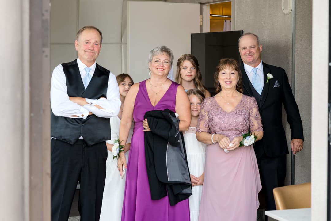 The parents and flower girls from a wedding watch as the couple has a first look.