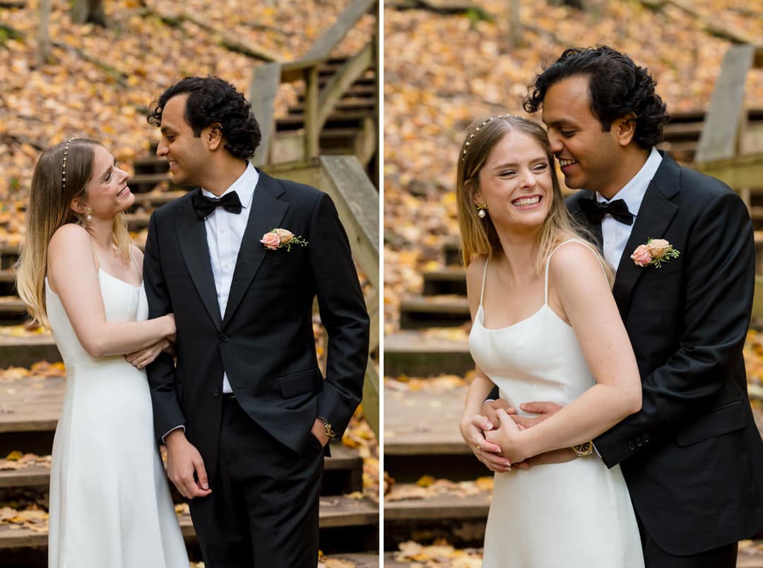 A bride and groom embrace near a set of wooden stairs on a leaf covered hillside in a park.