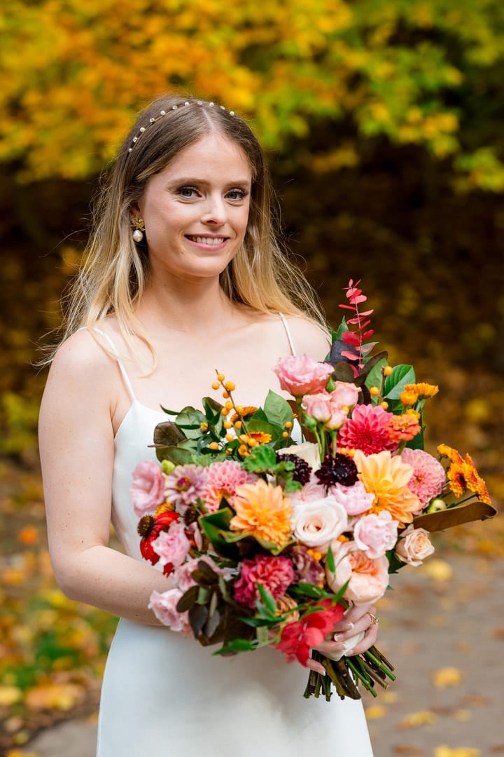 A bride wearing a white dress holds a colorful bouquet of flowers.