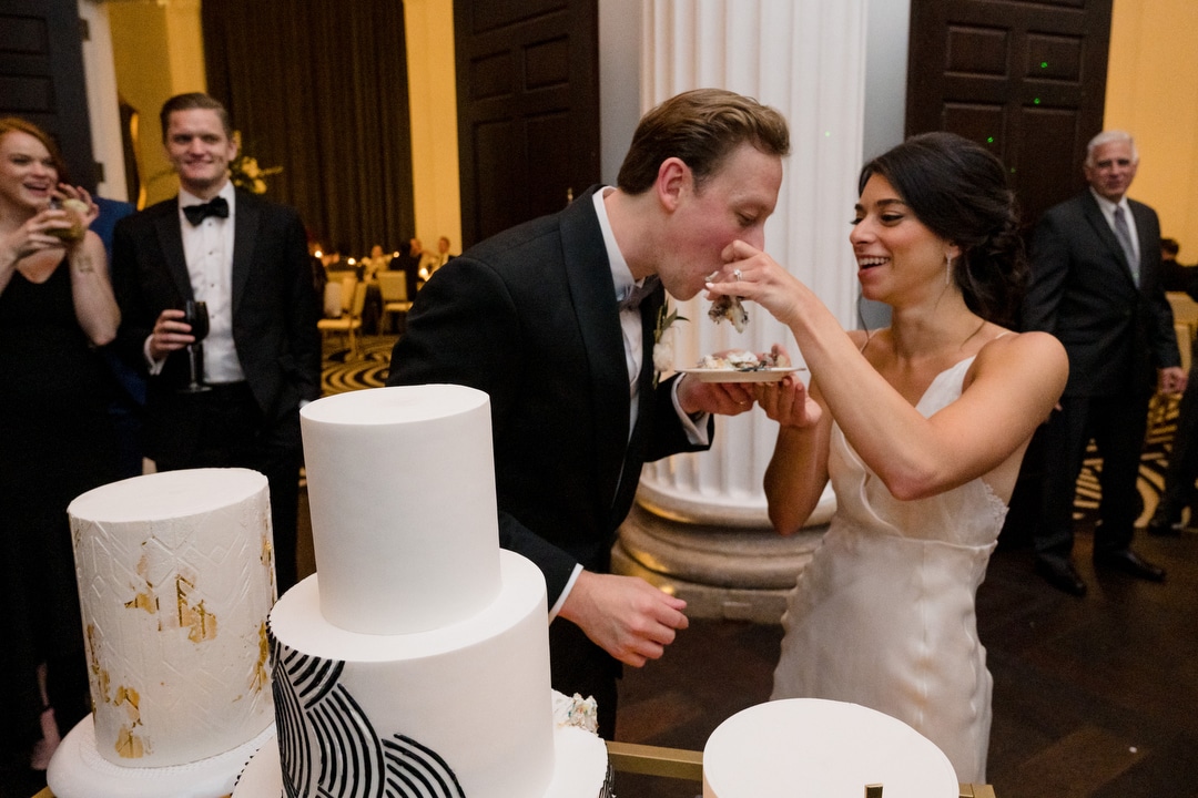 A bride feeds her groom a piece of cake during their elegant wedding at the Hotel Monaco in Pittsburgh.