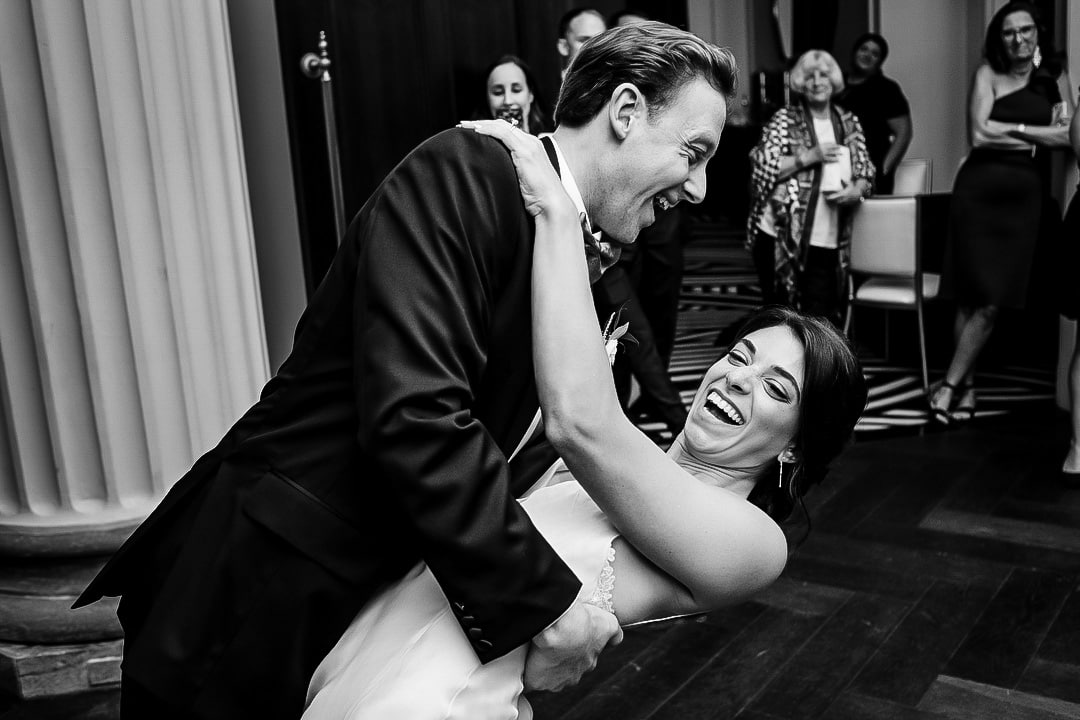 A bride laughs as the groom dips her at the end of their first dance during their elegant wedding at the Hotel Monaco in Pittsburgh.