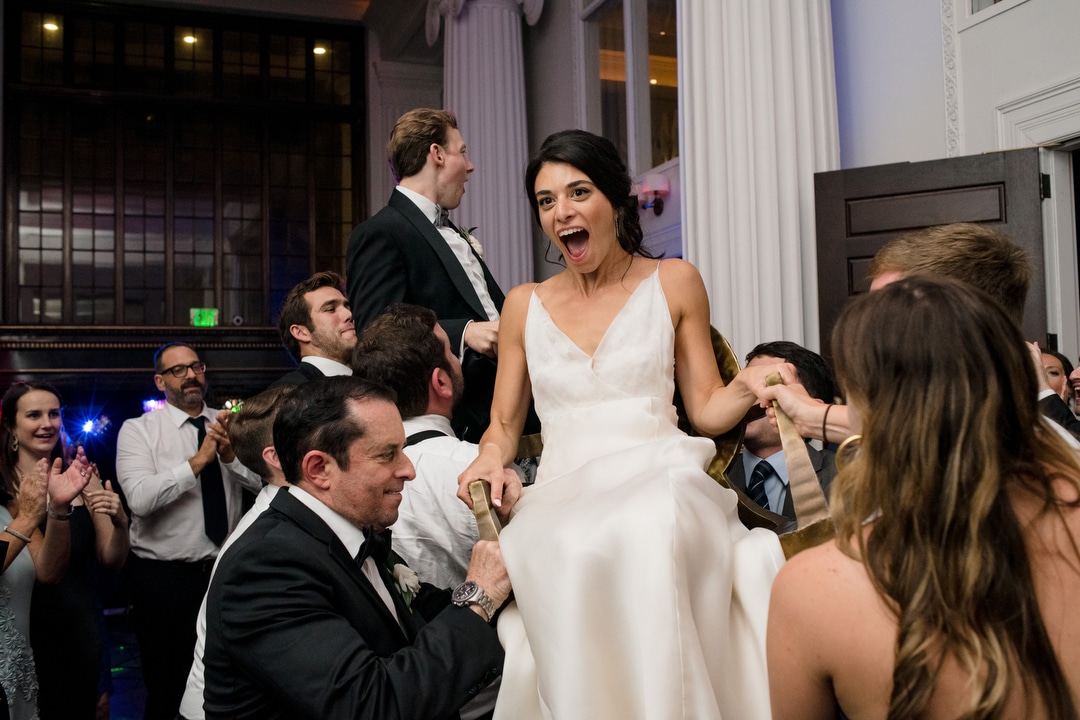 A bride laughs as she is lifted up on a chair during her wedding at the Hotel Monaco in Pittsburgh.