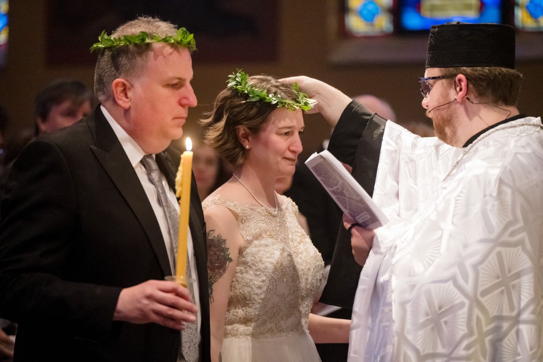 A priest places laurel crowns on the heads of a bride and groom during their wedding ceremony at Saint John Chrysostom church in Pittsburgh.