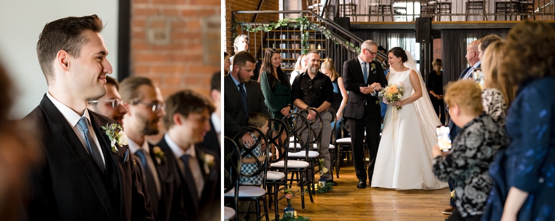 A bride in a white gown walks down the aisle with an older man amidst the intimate charm of The Art Room Wedding venue. Guests on either side stand in admiration as the groom, dressed in a dark suit, looks toward his bride. Warm light bathes the scene, enhancing its romantic allure.