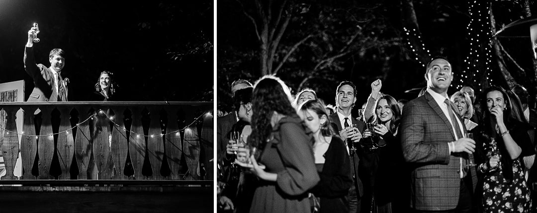A black-and-white photo captures a wedding scene at Springwood, with two people raising glasses on a lit wooden bridge to the left. On the right, a joyful Pittsburgh crowd gathers under string lights, drinks in hand. The setting is festive and lively.