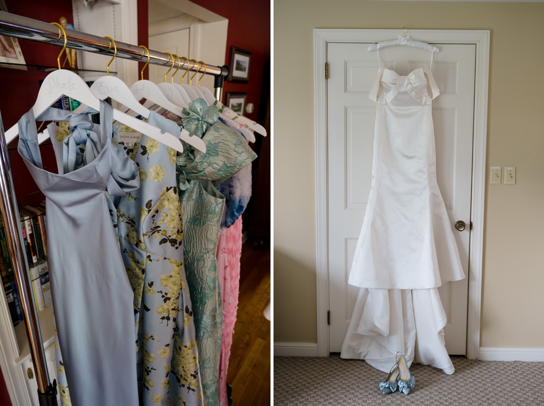 On the left, four pastel-colored bridesmaid dresses hang on labeled hangers. On the right, a white wedding gown and matching shoes hang on a door in a neutral-colored room.