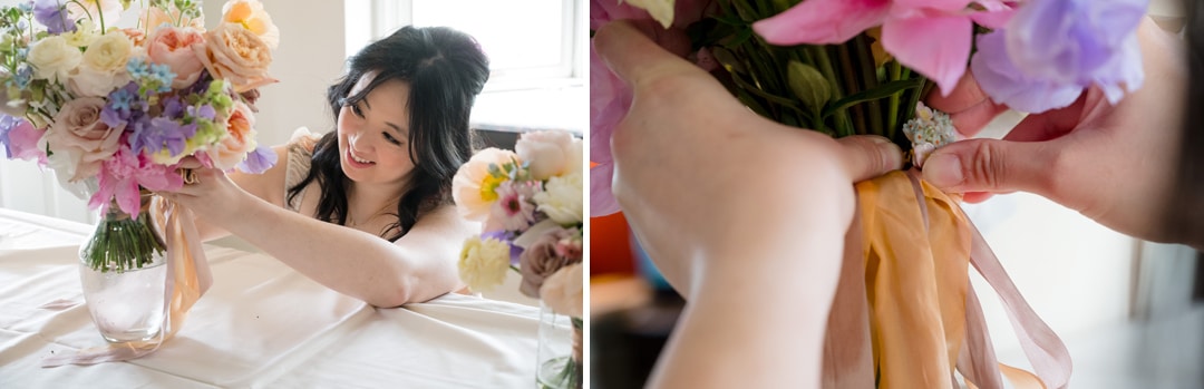 A smiling woman arranges pastel flowers in a vase on a table; close-up shows hands tying a peach-colored ribbon around the flower stems.