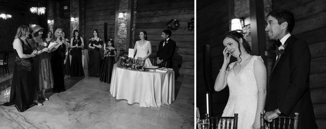 Black and white photo: Bridesmaids toast the bride and groom, who stand by a round table smiling. In a close-up, the bride wipes a tear while the groom smiles beside her during the wedding reception.