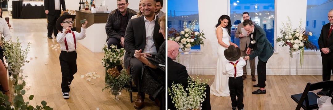 A young boy in a hat, red suspenders, and glasses walks down the aisle with a book at a wedding, then hands it to a couple standing at the altar, surrounded by smiling guests and floral arrangements.
